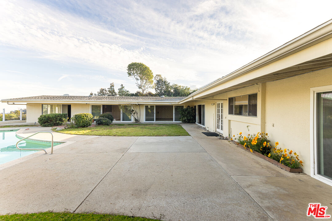1950 Carla Ridge Beverly Hills, CA 90210 - Photo 21 of 29 a view of a white house with a swimming pool and a yard