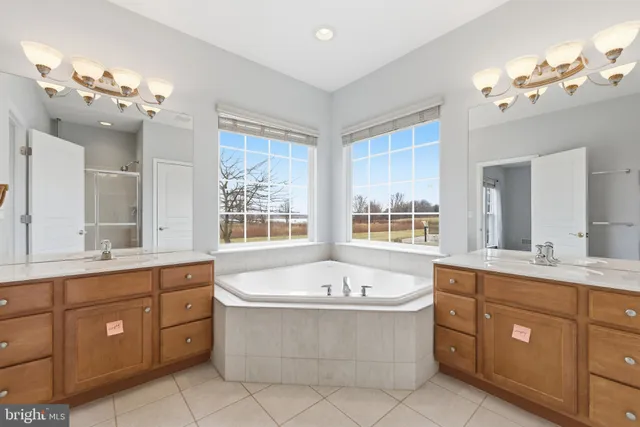 a spacious bathroom with a tub a double vanity sink a window a mirror and