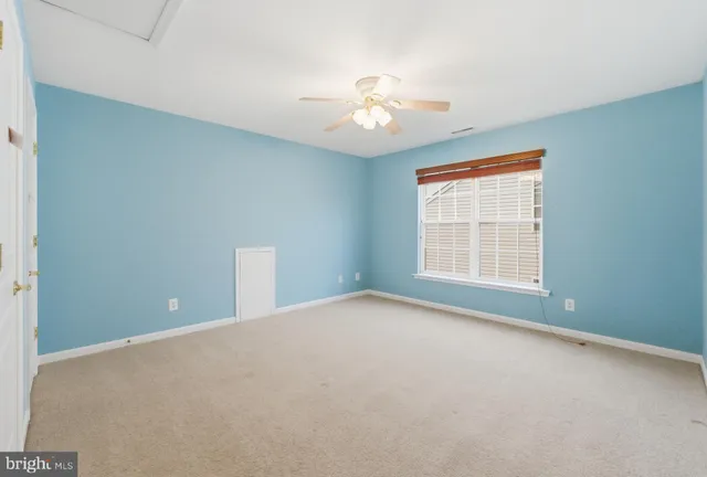 an empty room with chandelier fan and windows