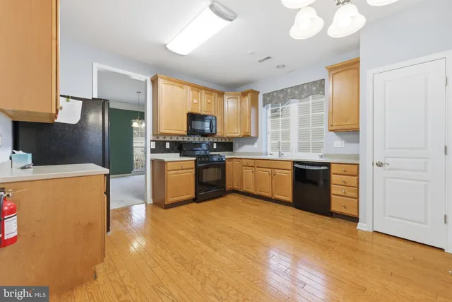 a kitchen with stainless steel appliances a sink a stove a refrigerator cabinets and a window