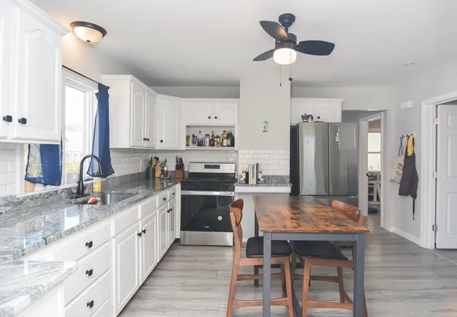 a kitchen with kitchen island granite countertop a table chairs refrigerator and cabinets