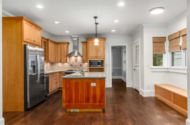 a kitchen with stainless steel appliances granite countertop a refrigerator a stove and a wooden floors