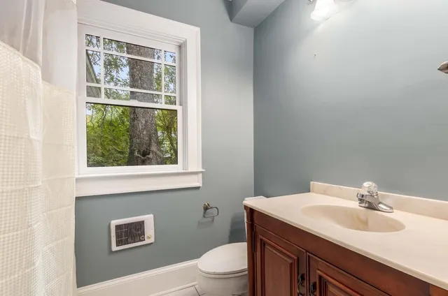 a view of an empty room with window and hardwood floor