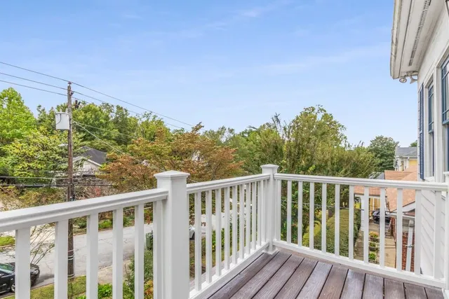 a view of an empty room with wooden floor and a ceiling fan