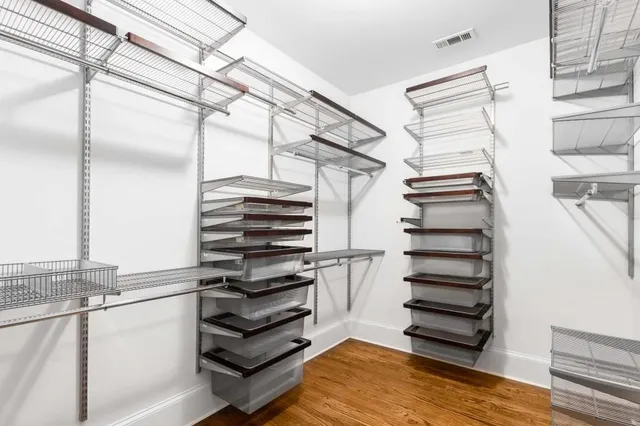 a view of an empty room with wooden floor and a ceiling fan