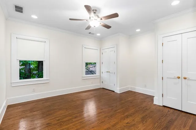 an empty room with wooden floor and fan