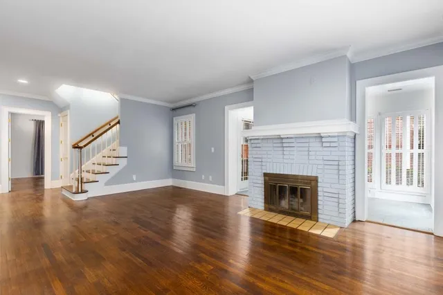 a view of an empty room with wooden floor fireplace and a window