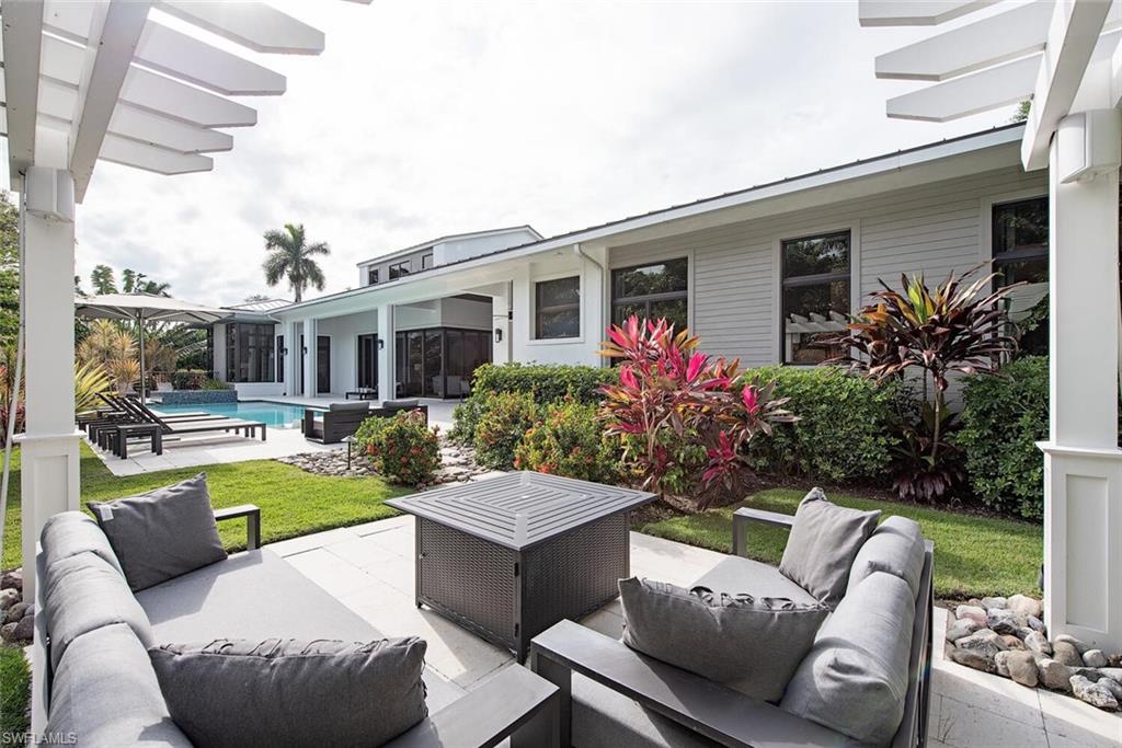 1300 Nautilus Road Naples, FL 34102 - Photo 7 of 21 a view of a patio with couches table and chairs potted plants and palm tree
