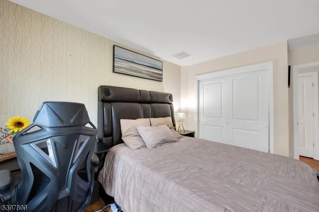 a bedroom with a bed a chair and potted plant on the table