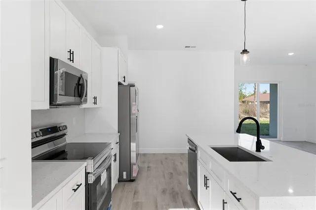 a kitchen with stainless steel appliances granite countertop a sink and a stove top oven with wooden floor