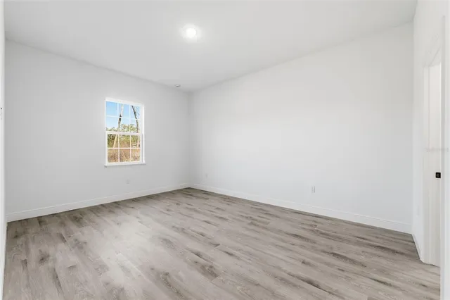 an empty room with wooden floor and a window