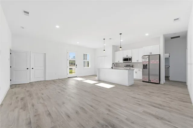 a view of a kitchen with refrigerator and white cabinets