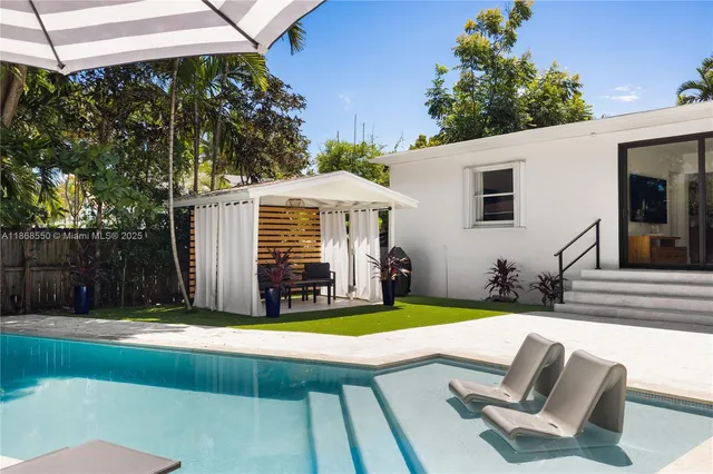 a view of a backyard with couches plants and large trees