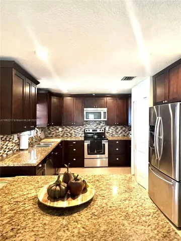 a kitchen with stainless steel appliances granite countertop a refrigerator and a stove top oven
