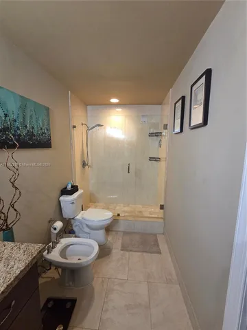 a bathroom with a granite countertop sink a toilet and shower