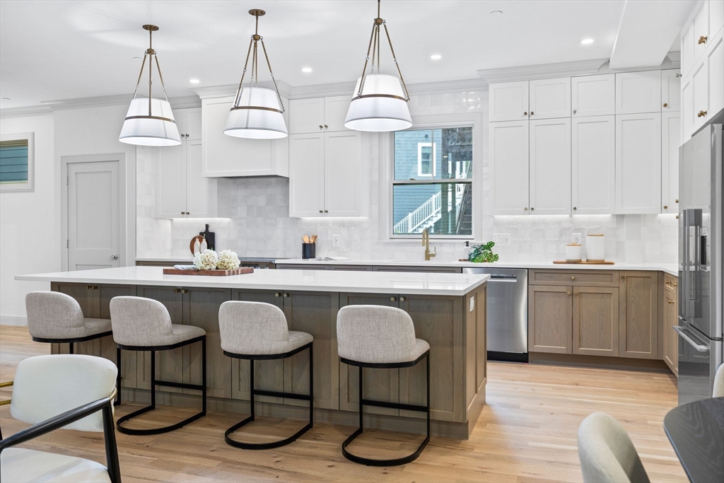 54 Springfield Street, Unit 1 Somerville, MA 02143 - Photo 3 of 38 a kitchen with stainless steel appliances granite countertop a sink a stove a dining table chairs and chandelier
