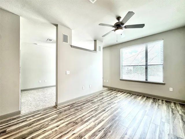 a view of an empty room with a window and wooden floor