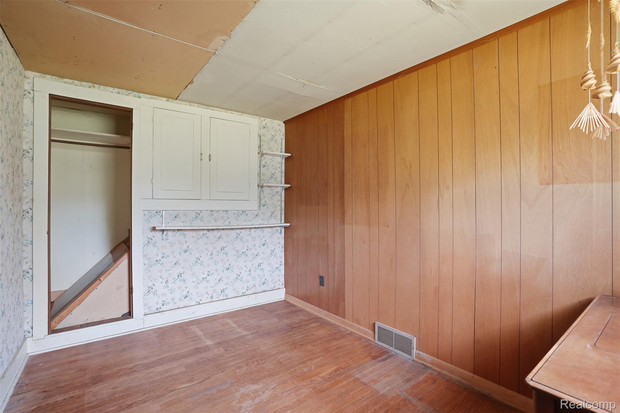 3405 West Coon Lake Road Howell, MI 48843 - Photo 18 of 36 Unfurnished bedroom with light wood-style flooring and wooden walls