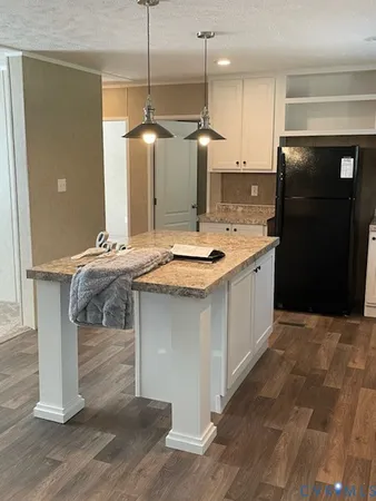 a kitchen with kitchen island granite countertop a sink a counter top space and stainless steel appliances