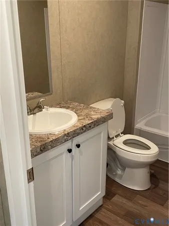 a bathroom with a granite countertop toilet a sink and a mirror