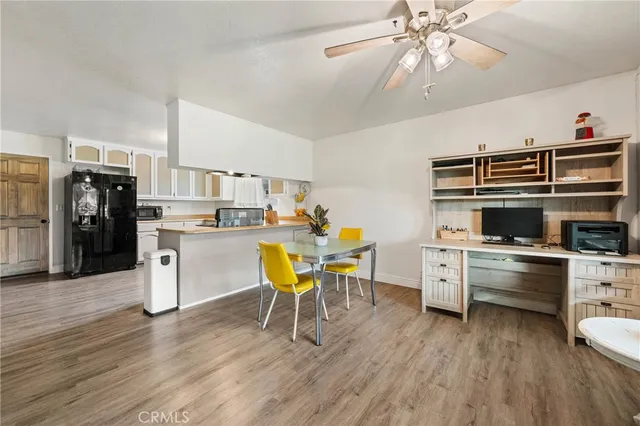 a kitchen with stainless steel appliances a stove a refrigerator a kitchen island a dining table and chairs with wooden floor