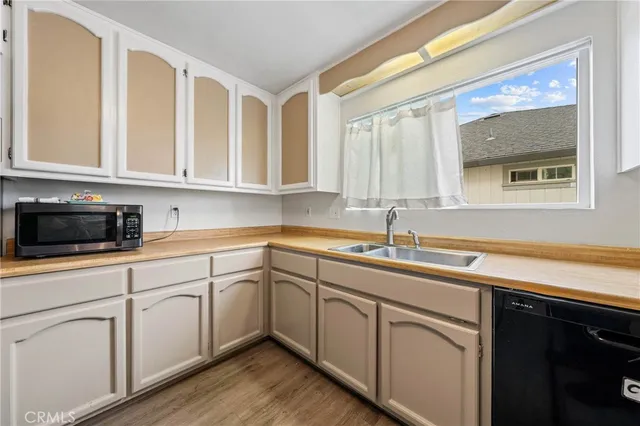 a kitchen with stainless steel appliances granite countertop white cabinets a sink and dishwasher next to a window