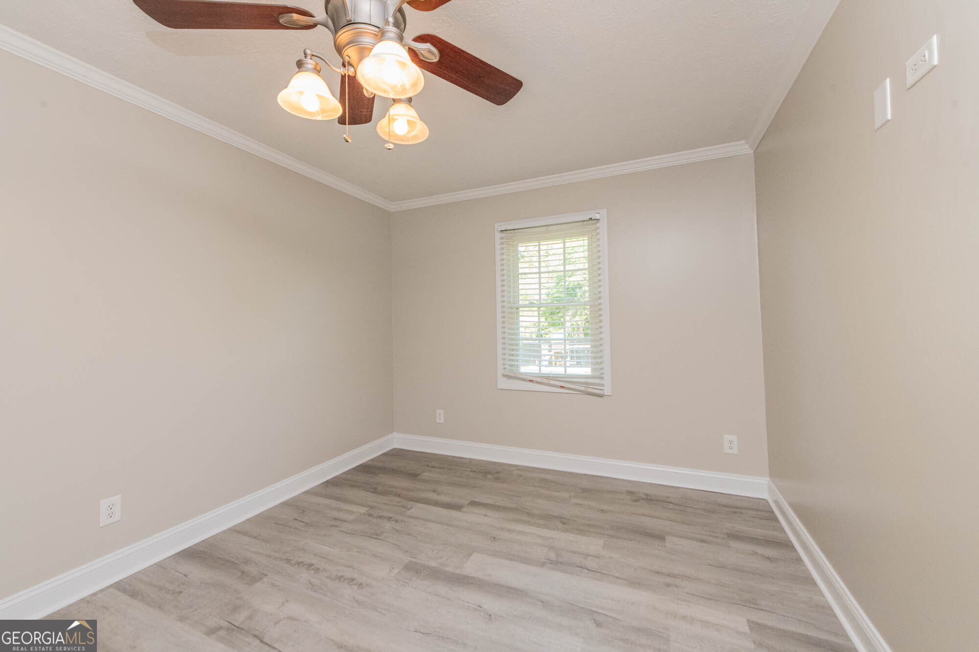 1661 Mule Creek Road Byron, GA 31008 - Photo 9 of 33 an empty room with wooden floor chandelier fan and windows
