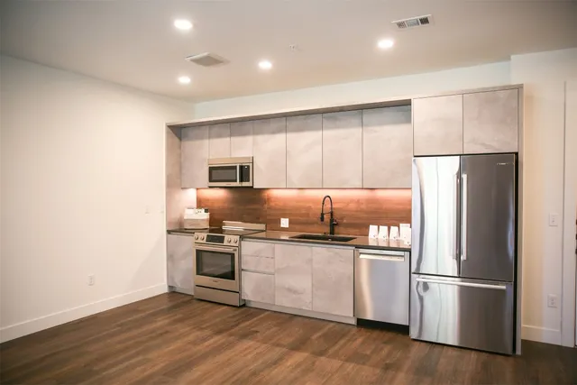 a kitchen with stainless steel appliances granite countertop a refrigerator and a stove top oven
