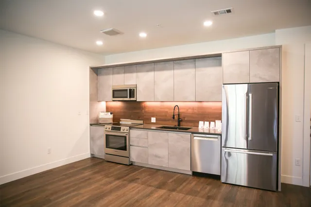 a kitchen with stainless steel appliances granite countertop a refrigerator and a stove top oven