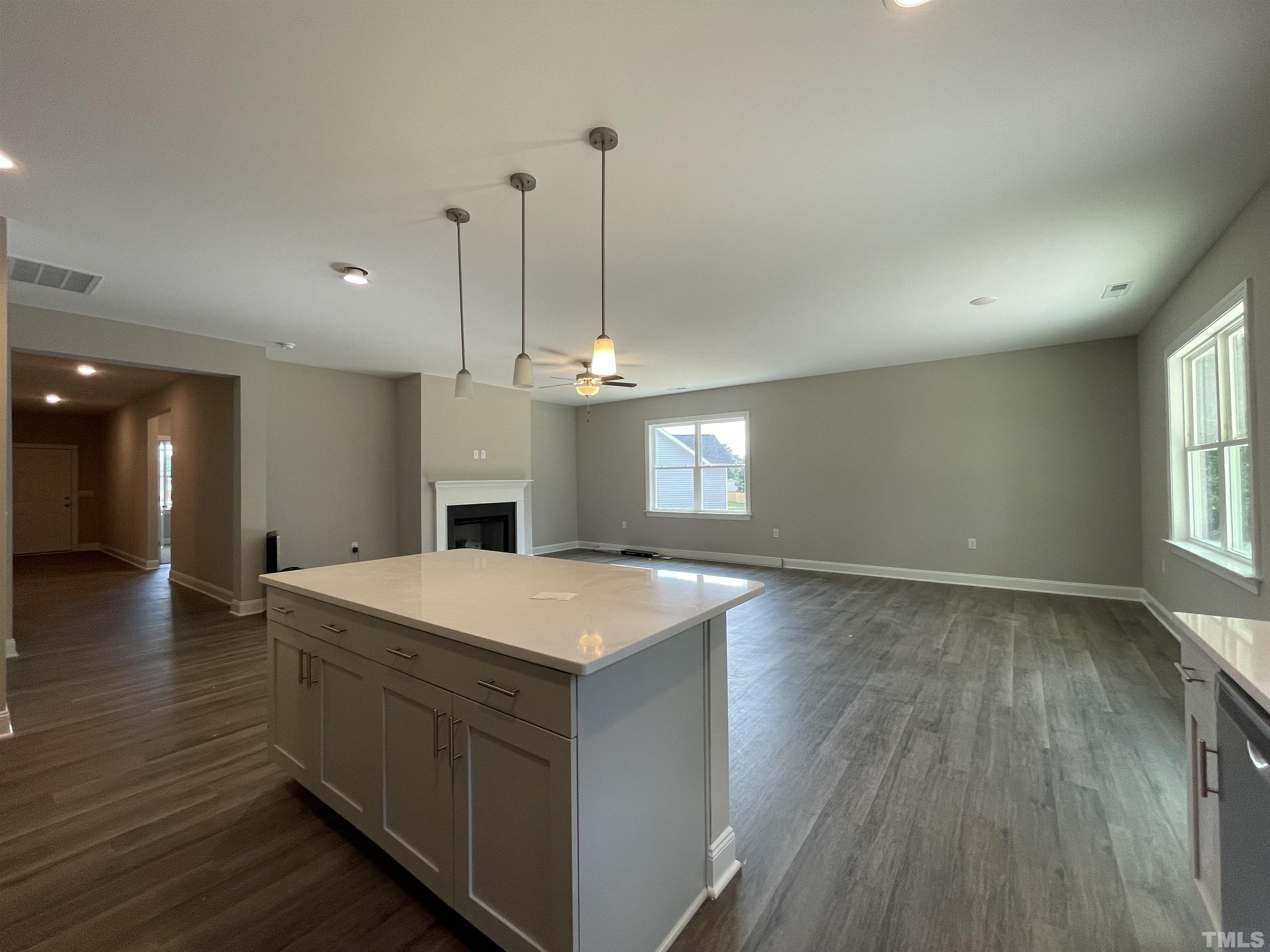 145 Wolf Ridge Willow Spring, NC 27592 - Photo 10 of 17 a hall with kitchen island a stove a wooden floor and a fireplace