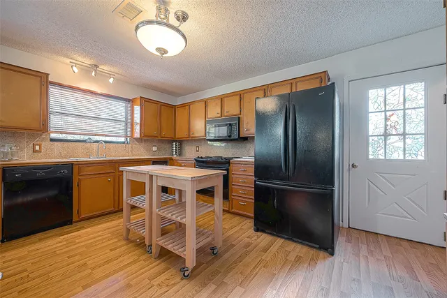 a kitchen with stainless steel appliances granite countertop a refrigerator a stove a sink dishwasher and a stove with wooden floor