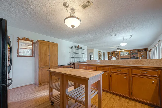 a kitchen with stainless steel appliances granite countertop a dining table chairs refrigerator and sink
