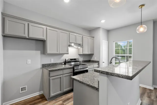 a kitchen with granite countertop a sink a stove and cabinets