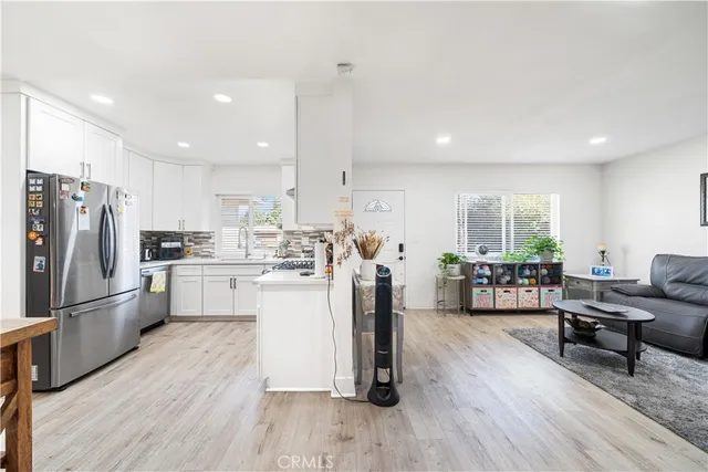 a kitchen with a refrigerator a sink dishwasher a couches and chairs with wooden floor