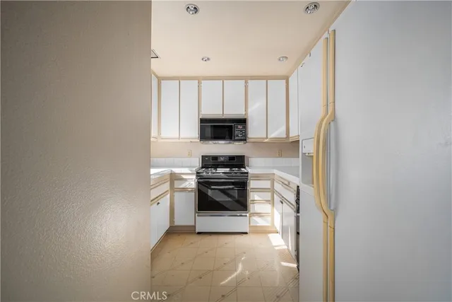 a kitchen with granite countertop stove top oven microwave and cabinets