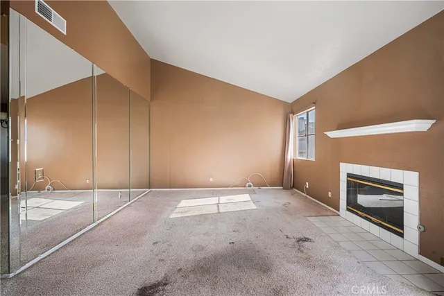 a view of an empty room with a fireplace and a window