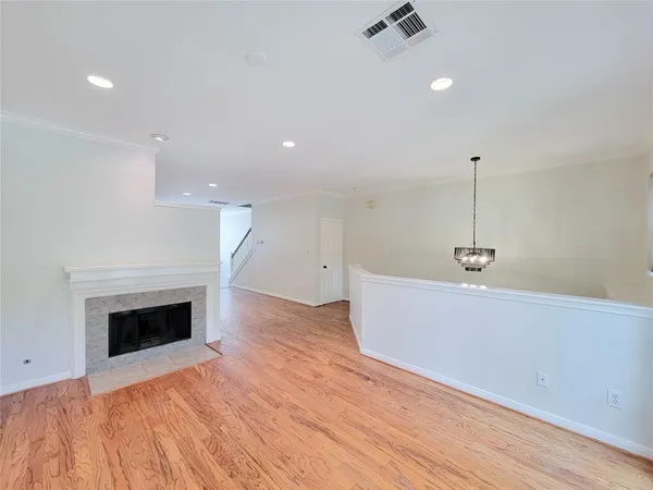 a view of an empty room with wooden floor and a fireplace