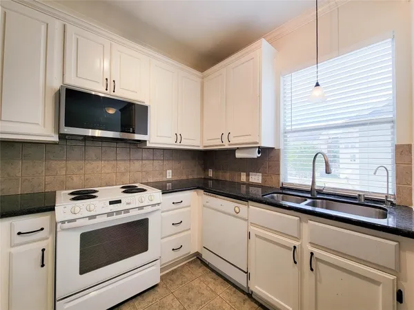 a kitchen with granite countertop white cabinets white stainless steel appliances and a sink