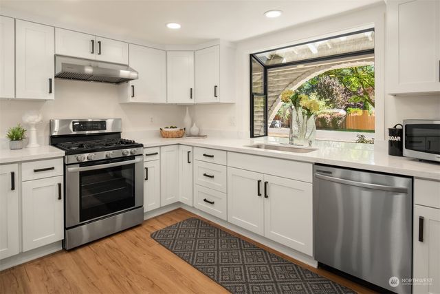 a kitchen with stainless steel appliances white cabinets and a stove top oven