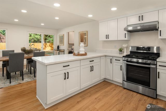 a kitchen with white cabinets stainless steel appliances and wooden floor