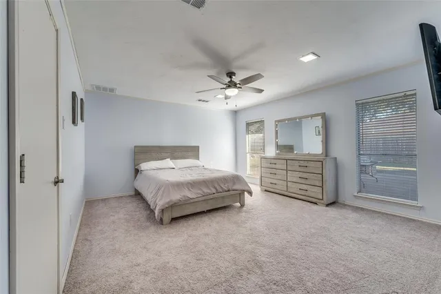 a spacious bedroom with a bed a dresser and a chandelier