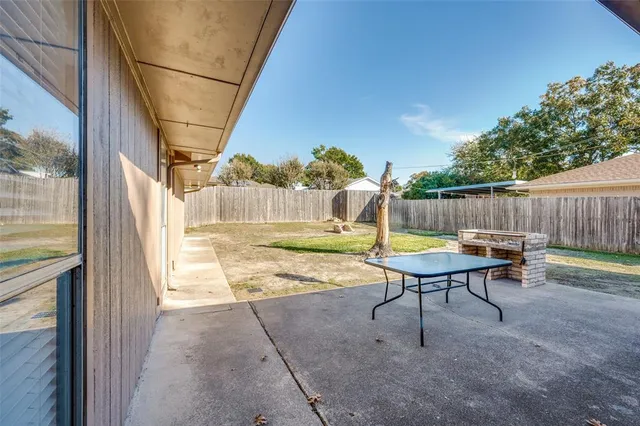a view of a backyard with table and chairs and wooden fence