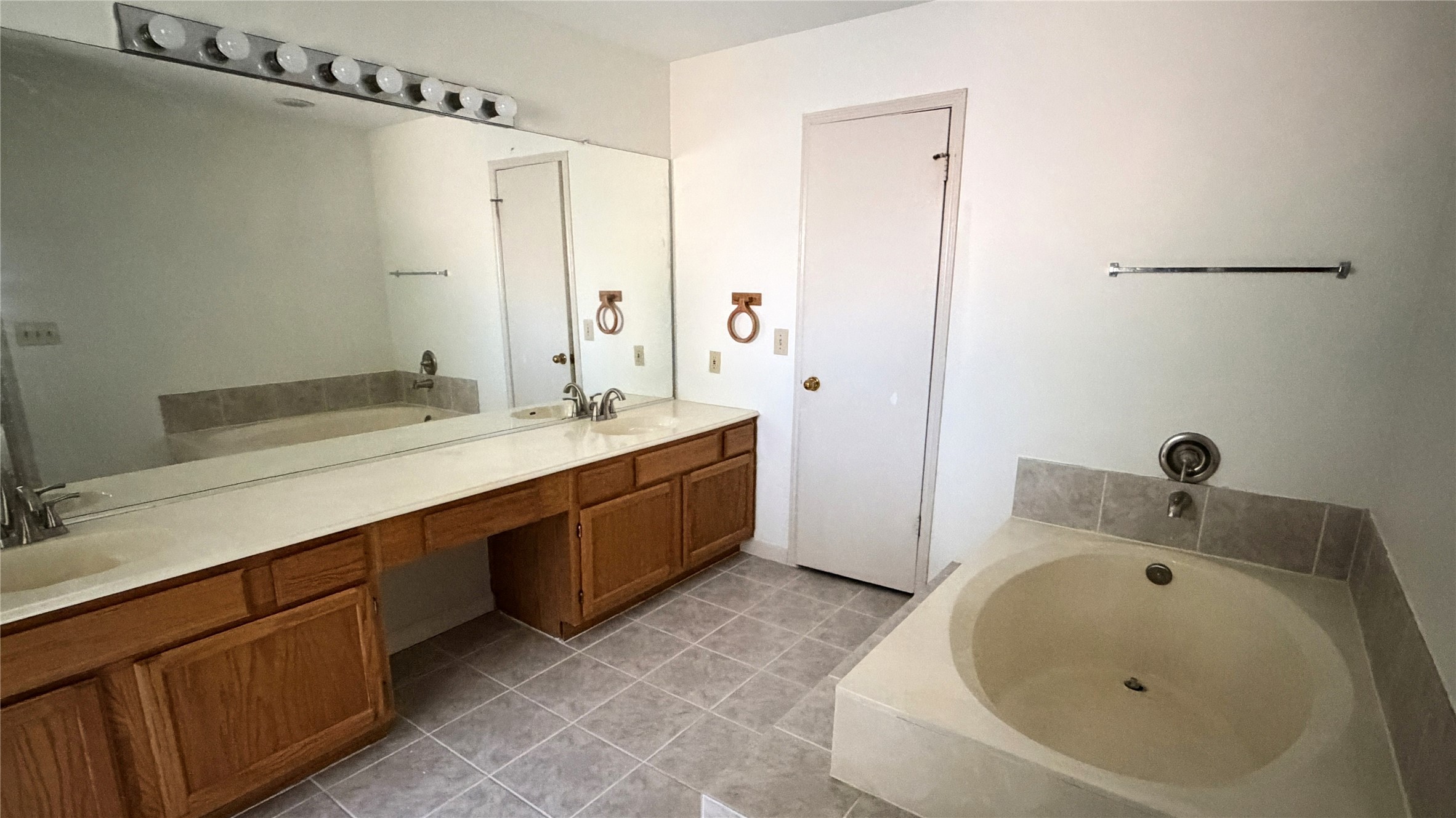 7771 Springville Drive Houston, TX 77095 - Photo 10 of 13 Luxurious primary bathroom featuring double sinks, a spacious mirror, and a relaxing soaking tub.