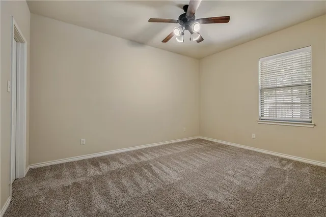 an empty room with a chandelier fan and windows