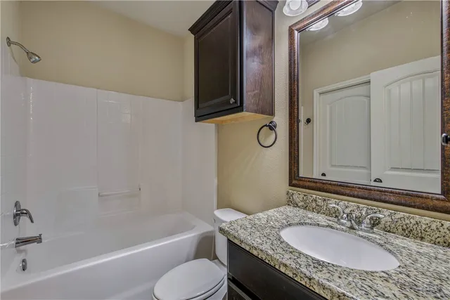 a bathroom with a granite countertop tub sink and mirror