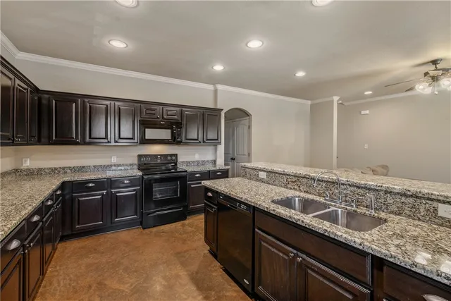a large kitchen with granite countertop stainless steel appliances and wooden cabinets