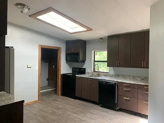 a kitchen with granite countertop cabinets stainless steel appliances a sink and a window