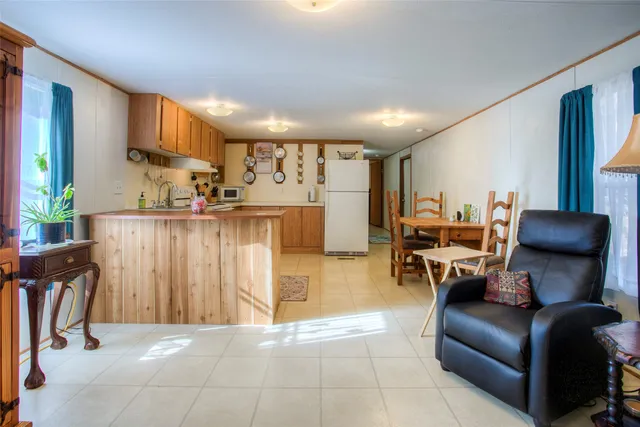a living room with furniture a wooden floor and a kitchen