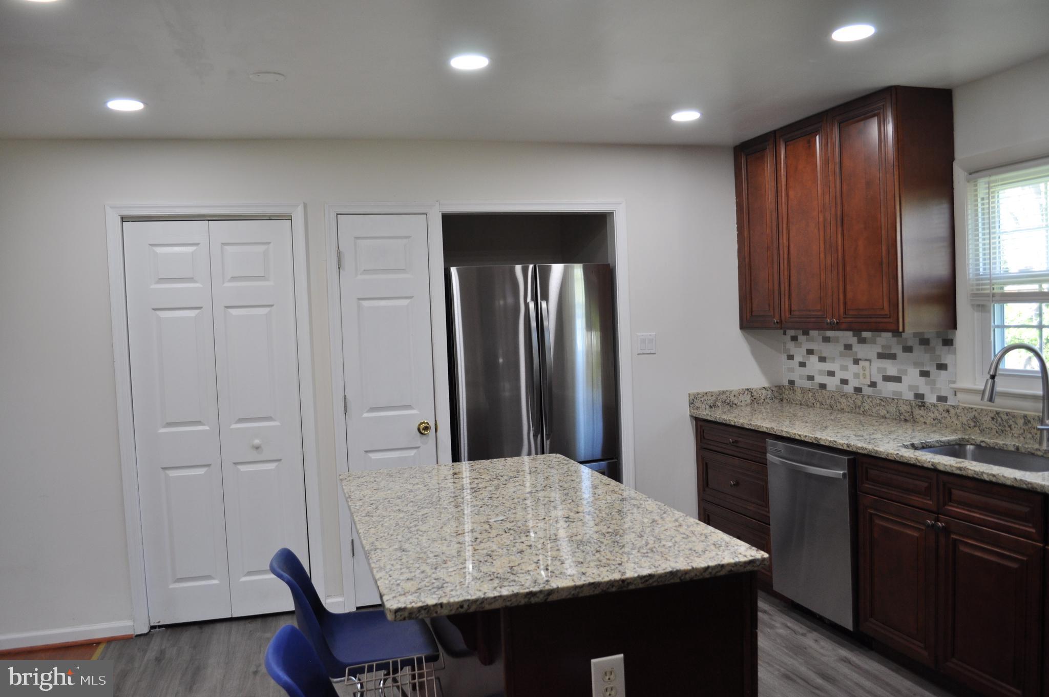 11809 Milbern Drive Potomac, MD 20854 - Photo 13 of 36 a kitchen with kitchen island granite countertop wooden cabinets a refrigerator and a sink