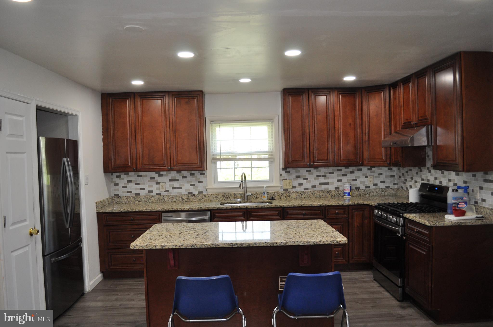 11809 Milbern Drive Potomac, MD 20854 - Photo 10 of 36 a kitchen with kitchen island stainless steel appliances a sink stove and refrigerator